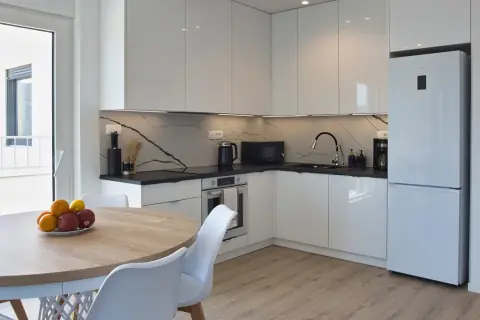 Biała kuchnia z lodówką i piekarnikiem w apartamencie 8
